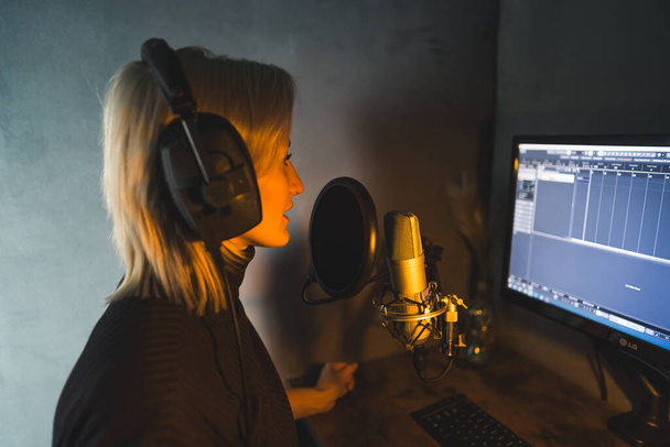 Bir radyo istasyonunda sunucu olarak çalışan genç bir kadın, orta ölçekli bir görüntü, podcast stüdyosu. Yüksek kalite fotoğraf - Fotoğraf, Görsel