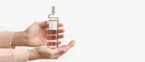Mani femminili con bottiglia di profumo su sfondo bianco con spazio per il testo - Foto, immagini