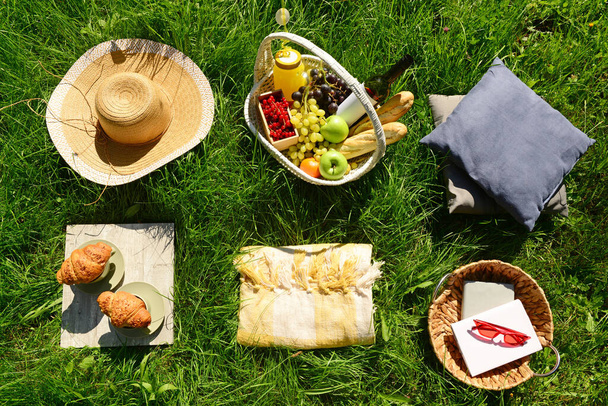 Set de picnic romántico con canasta de mimbre llena de sabrosa comida y bebidas sobre hierba en el parque - Foto, Imagen