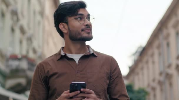 Onnellinen onnistunut tyytyväinen Intian etninen mies nuori kaveri liikemies mies matkapuhelin käyttäjä pidä älypuhelimen kädet tekstiviesti chattailuun sosiaalisen median turisti verkossa GPS kartta ulkona kaupunkien katu - Materiaali, video