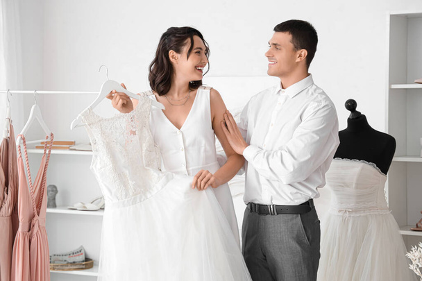 Young couple choosing wedding dress in office - Foto, imagen