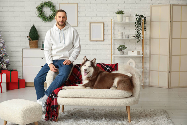 Handsome young man with cute Husky dog at home - Photo, image