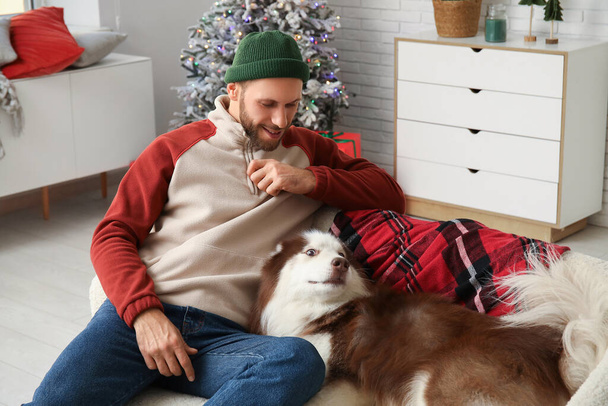 Bello giovane uomo con cane carino Husky a casa la vigilia di Natale - Foto, immagini
