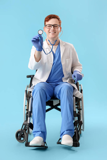 Mavi arka planda steteskobu olan tekerlekli sandalyedeki erkek doktor. - Fotoğraf, Görsel