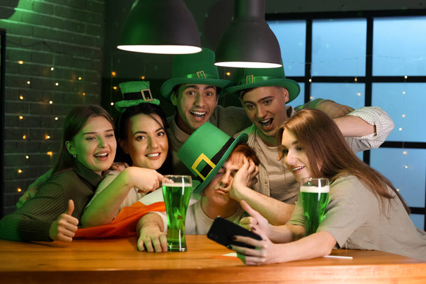 Gruppo di giovani con birra che si fanno selfie al pub il giorno di San Patrizio - Foto, immagini