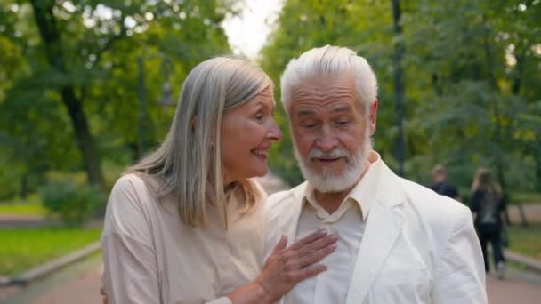 Nyugdíjas boldog mosolygós kaukázusi idős pár család család férfi nő nagypapa feleség férj beszél aktív nevetés séta együtt kívül park friss levegő egészségügyi kapcsolat nyugdíj - Felvétel, videó