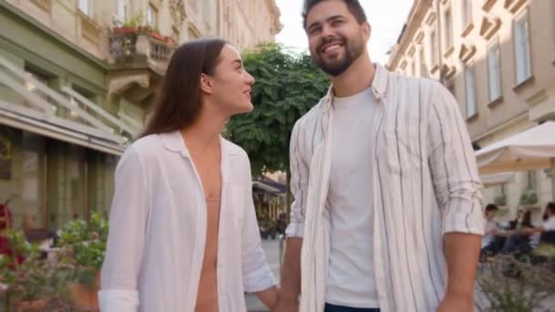 Young couple walking city street outside together Caucasian man woman talking chatting sightseeing tourism trip honeymoon happiness love joy smile touching fun travelling tour beloved sweetheart bond - Footage, Video