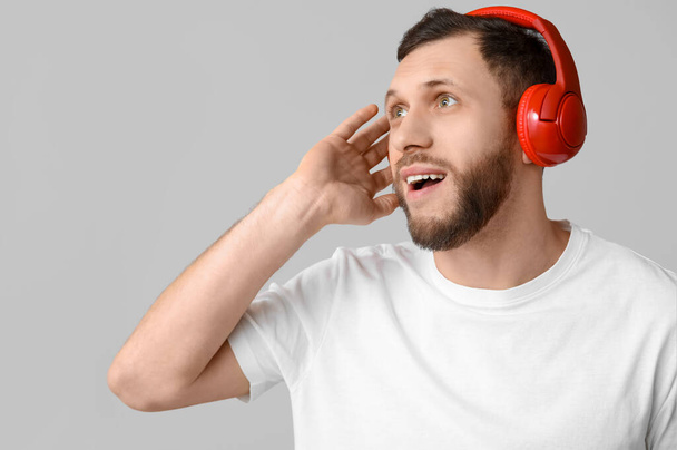 Νεαρός με σύγχρονα ακουστικά σε γκρι φόντο - Φωτογραφία, εικόνα
