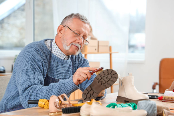 Férfi cipőpucoló csizma asztalnál a műhelyben - Fotó, kép