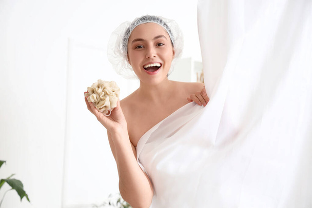Mujer joven con esponja detrás de la cortina tomando baño en casa - Foto, Imagen