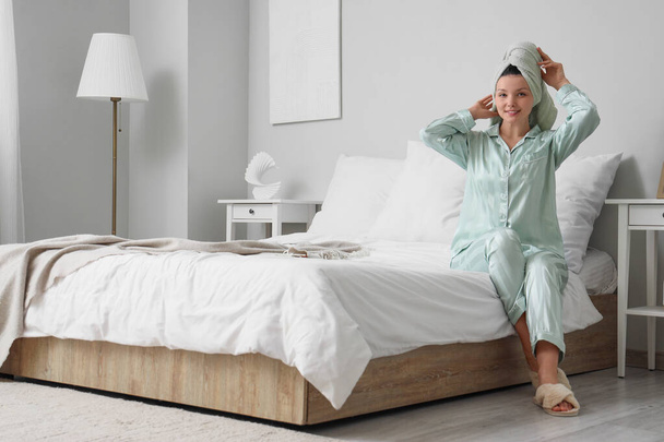 Молодая женщина с полотенцем после душа сидит в спальне - Фото, изображение