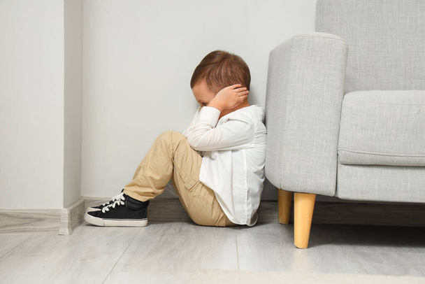 Osamělý malý chlapec s autistickou poruchou sedí na podlaze doma - Fotografie, Obrázek