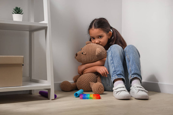 Menina asiática com transtorno autista e urso de brinquedo sentado no canto em casa - Foto, Imagem