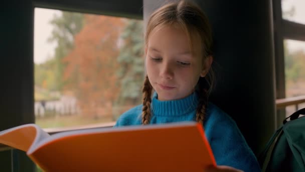 Küçük kızıl saçlı Avrupalı kız oturmuş not defteri okuyor. Okul ödevi okuyor. Pencereye bakıyor. - Video, Çekim