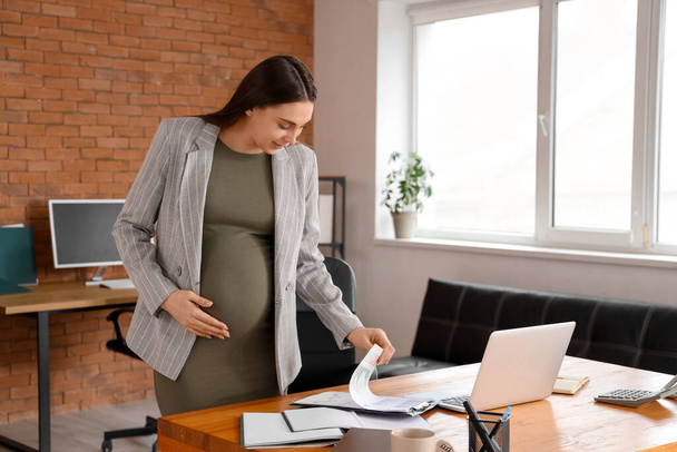 Donna d'affari incinta con documenti che lavorano in ufficio - Foto, immagini