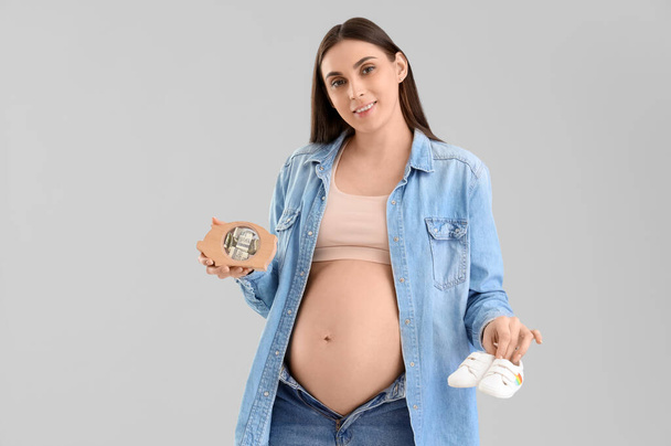 Genç hamile bir kadın domuz kumbarası ve arka planda bebek poposu var. Annelik Faydası kavramı - Fotoğraf, Görsel