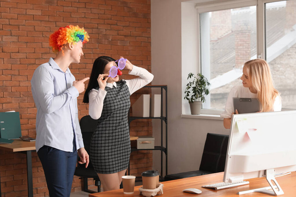 Ділові люди з кумедними маскуваннями в офісі. Святкування Дня дурнів - Фото, зображення