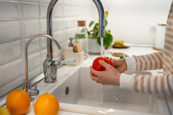 Γυναίκα χέρια πλύσιμο νωπών κόκκινες πιπεριές πάπρικα στο σπίτι κουζίνα για σαλάτα. Φυσικά βιολογικά συστατικά για υγιεινή διατροφή βιταμινών. Απόλαυση από vegan ωμά κουζίνα. Καθαρισμός σε λαχανικά και φρούτα - Φωτογραφία, εικόνα