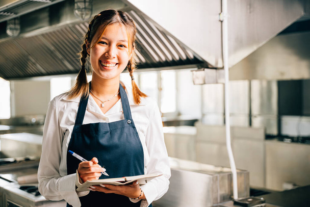 Professional chefs portrait in commercial kitchen. Holding note book pen for teaching. Expertise in education explaining skills. Working confidently presenting ideas to colleagues. Foor education - 写真・画像