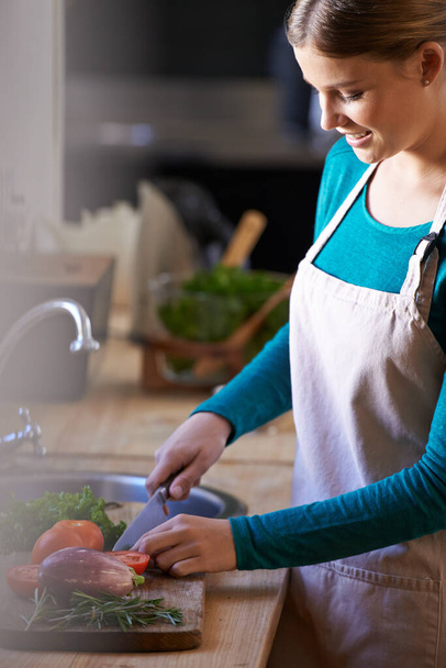 Food, cooking and woman with vegetables in kitchen cutting ingredients with knife at home. Happy, groceries and portrait of female person with produce for dinner, supper or meal at apartment - Photo, Image