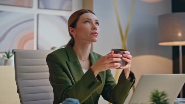 Menedżer trzyma filiżankę kawy odpoczywającą w biurze. Pensive kobieta cieszyć gorący napój relaks po pracy sam. Przemyślana bizneswoman patrząca na odległość. Przygnębiony biznes menedżerski  - Materiał filmowy, wideo