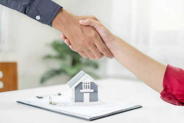Biznesmeni i maklerzy agenci nieruchomości uścisną sobie dłonie po zakończeniu negocjacji w sprawie ubezpieczenia domu i podpisania umów. koncepcja ubezpieczenia domowego. - Zdjęcie, obraz