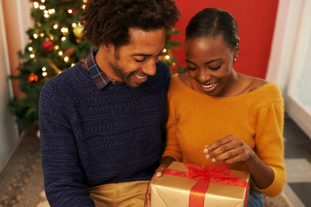 Weihnachten, Geschenk und schwarze Pärchen, die eine Schachtel oder Eröffnungsüberraschung an festlichen Feiertagen oder im Urlaub mit Glück schenken. Aufgeregt bieten Frau und Mann zu Hause ein Geschenk mit Liebe und Freundlichkeit in der Ehe. - Foto, Bild