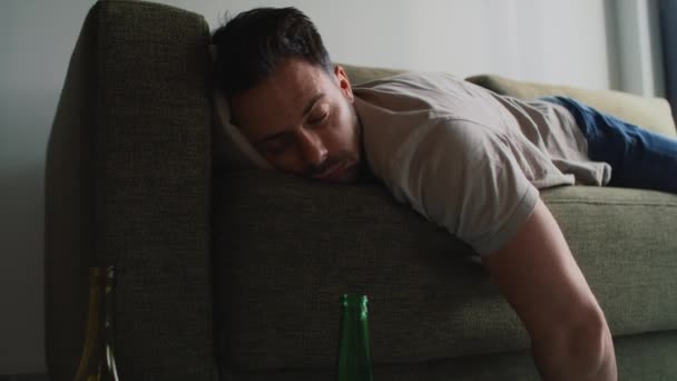 Pijany mężczyzna leżący na kanapie wśród pustych butelek - Materiał filmowy, wideo