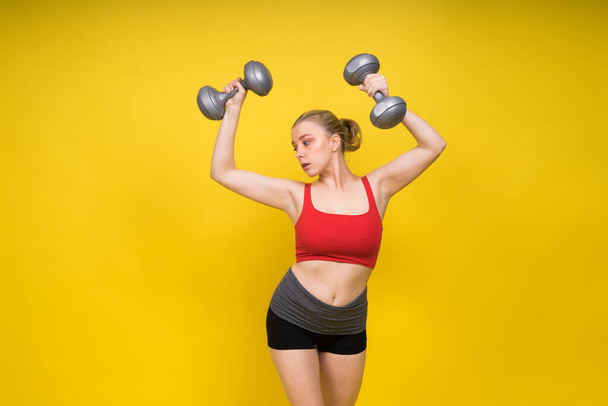 Lächelnde junge mollige Fitness sportlich verführerische Frau beim Training mit einer Hantelstange - Foto, Bild