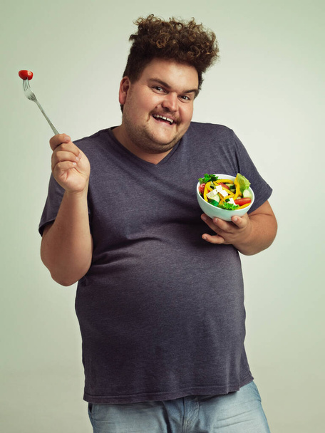 Studio, πορτρέτο και υπέρβαρος άνθρωπος με σαλάτα για απώλεια βάρους, διατροφή και υγιεινό γεύμα με διατροφή. Παχύσαρκο, αρσενικό άτομο και χαμόγελο με βιολογική τροφή για αποτοξίνωση, αλλαγή τρόπου ζωής και οφέλη από τη βιταμίνη C. - Φωτογραφία, εικόνα
