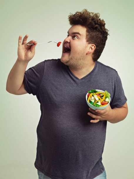 Studio, man and eating salad for weight loss, healthy diet and lifestyle benefits for wellness. Plus size, male person and fork with organic food for nutrition, vitamin c and hungry with lunch meal. - Photo, Image