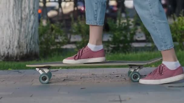 Uma adolescente joga um skate no pavimento e começa a andar ao longo do beco, perto de suas pernas. Uma jovem mulher extrema se move ao redor da cidade em um longboard, tênis com um grande plano. - Filmagem, Vídeo