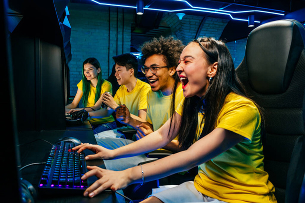 Multiethnic group of young friends playing videogames - Team of professional esport gamers playing in competitive video games on a cyber games tournament - Photo, image