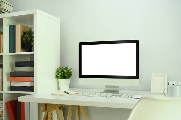 Mock up számítógép monitor, szobanövény, notebook és kávéscsésze fehér asztalon. - Fotó, kép