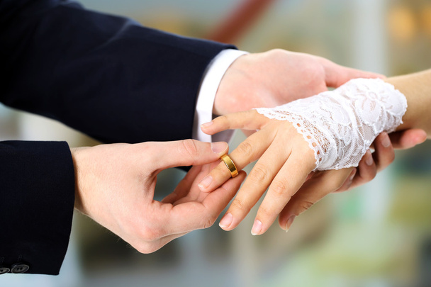 Woman and man holding wedding rings, close-up, on bright background - 写真・画像