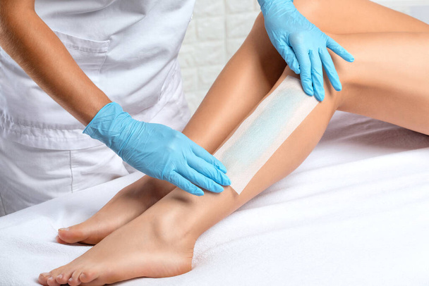 Un esthéticien fait une épilation des jambes d'une femme dans un salon de beauté. Cosmétologie esthétique féminine. - Photo, image
