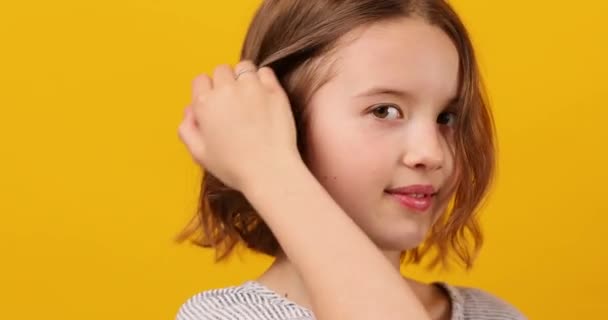 Ein gelassenes Schulmädchen posiert nachdenklich mit der Hand auf der Wange vor gelbem Hintergrund. - Filmmaterial, Video