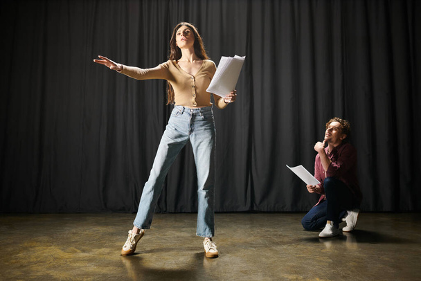 Kobieta stoi pewnie przed mężczyzną trzymającym papiery podczas prób teatralnych.. - Zdjęcie, obraz