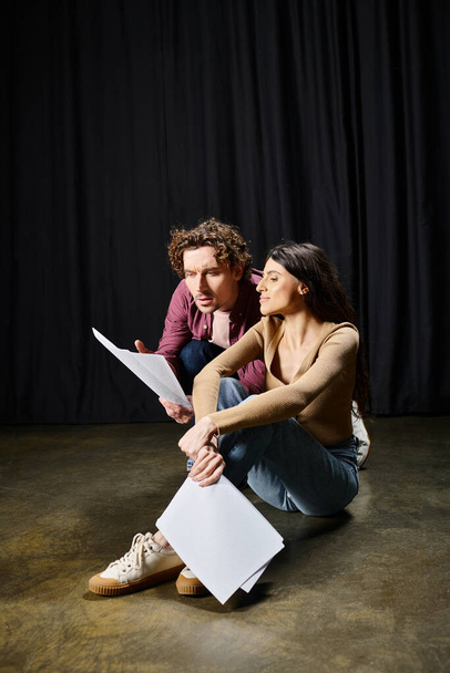 Ein gut aussehender Mann und eine gut aussehende Frau sitzen bei Theaterproben eng am Boden. - Foto, Bild