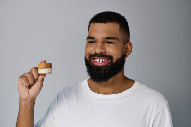 Handsome man with a beard holding cream. - Photo, Image