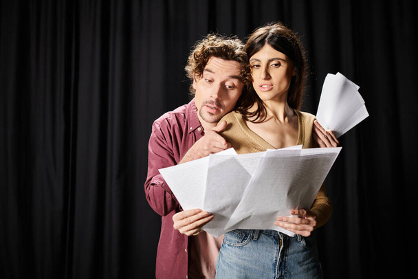 Ein Mann und eine Frau mit Papieren vor schwarzem Hintergrund. - Foto, Bild