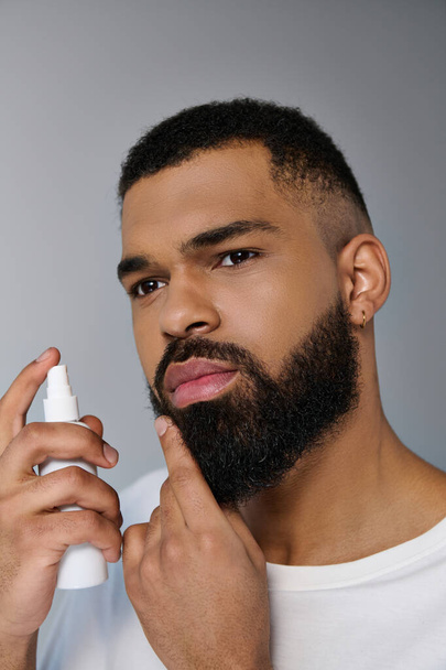 Afroamericano giovane uomo con la barba applicazione locion sul suo viso. - Foto, immagini