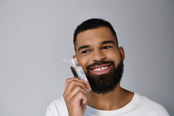 African american appealing man with a beard applying locion on his face. - Photo, Image
