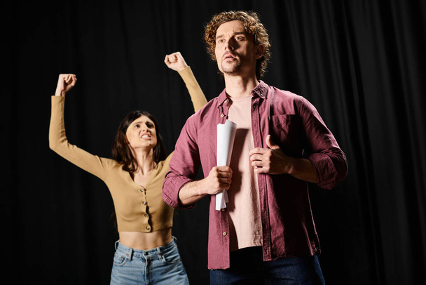 Ένας άνδρας και μια γυναίκα στέκονται με αυτοπεποίθηση μπροστά από ένα μικρόφωνο κατά τη διάρκεια των προβών σε ένα θέατρο. - Φωτογραφία, εικόνα