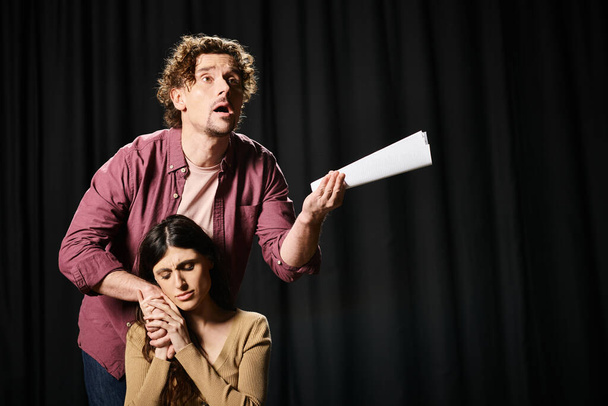 En un ensayo de teatro, un hombre guapo está al lado de una mujer sosteniendo un papel. - Foto, imagen