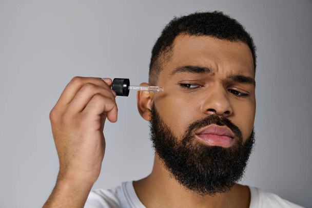 Afrikai-amerikai jóképű fiatalember szakállal, kezében egy üveg szérummal.. - Fotó, kép