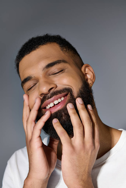 Smiling man with beard, hands on face. - Photo, Image