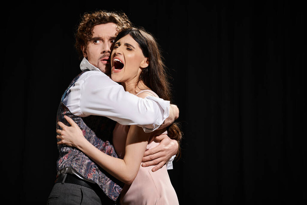 Un hombre guapo y una hermosa mujer abrazándose en un tierno abrazo durante los ensayos de teatro. - Foto, imagen