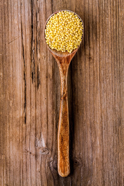 organic millet seeds in a wooden spoon closeup - 写真・画像