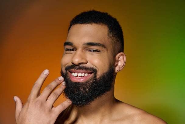 Un giovane sorridente con la barba che mostra la sua routine di cura della pelle. - Foto, immagini